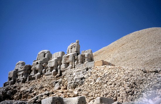 Die Statuen, von denen die Köpfe fielen. Im Hintergrund der aufgeschüttete Grabhügel