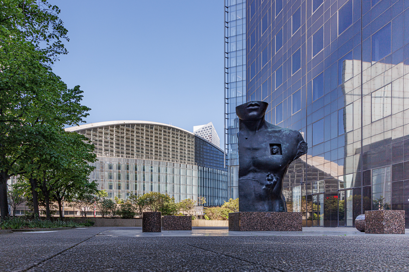 Seit 1983 steht auf einem Granitpflaster am Fu&szlig;e des Tour Areva eine Bronzeb&uuml;ste eines verk&uuml;rzten Riesen, die an die Statuen erinnert, die uns die Antike hinterlassen hat. Mit dieser Skulptur m&ouml;chte der K&uuml;nstler Igor Mitoraj die Passanten daran erinnern, dass Geschichte und Erinnerung in diesem noch jungen Stadtteil eines Tages einen wichtigen und notwendigen Platz einnehmen werden