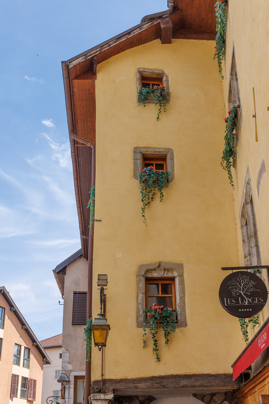 Hauswand mit Blumenfenstern und alter Lampe