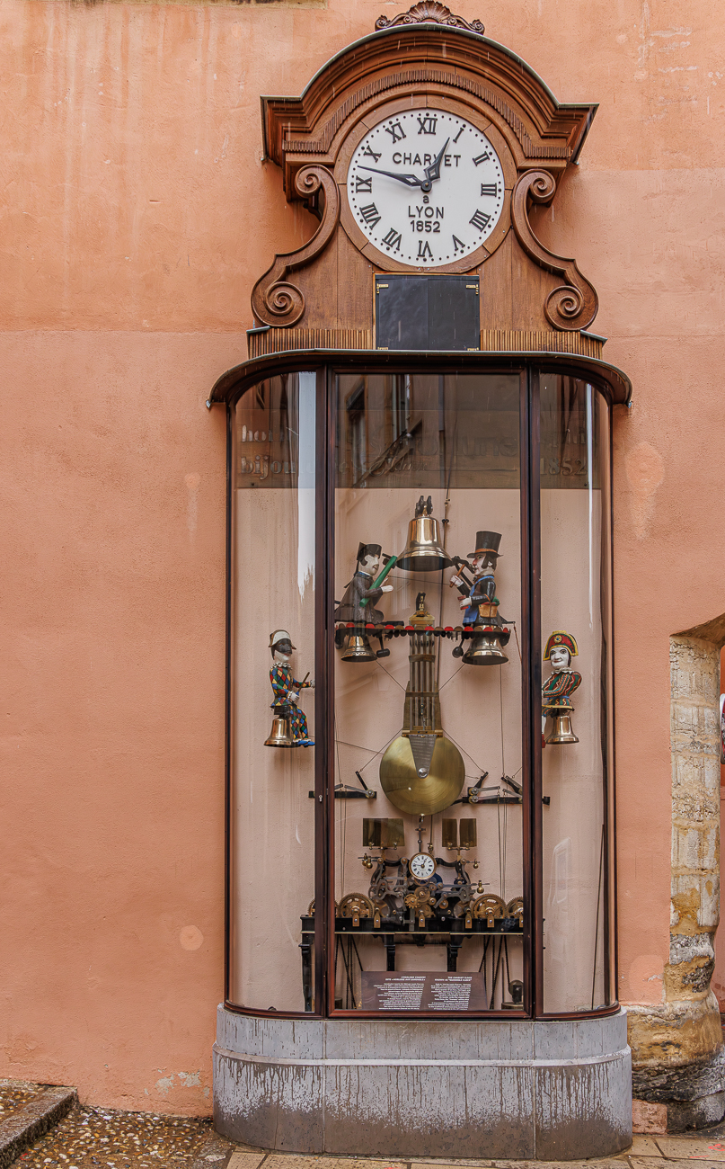 Dies ist die historische Charvet-Uhr (Horloge Charvet), die urspr&uuml;nglich 1864 f&uuml;r ein Kurzwarengesch&auml;ft gebaut wurde. Sie ist auch als "Guignol-Uhr" bekannt, da sie Automatenfiguren der ber&uuml;hmten Lyoner Puppenspielcharaktere wie Guignol und Gnafron enth&auml;lt. Die Uhr wurde aufwendig restauriert und befindet sich seit Januar 2021 an der Fassade des H&ocirc;tel de Gadagne im Stadtteil Vieux Lyon. Das monumentale Uhrwerk ist etwa sieben Meter hoch und spielt alle 15 Minuten Westminster-Glockenspiele.