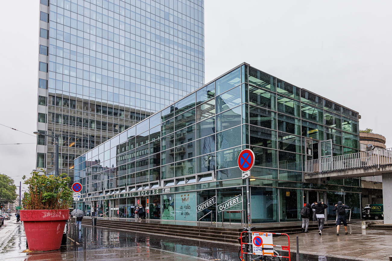 Wer nach Lyon reist, muss auch die ber&uuml;hmte Markthalle Halles de Lyon-Paul Bocuse gesehen haben. Die Zentrale Markthalle von Lyon wurde nach dem ber&uuml;hmtesten aller franz&ouml;sischen K&ouml;che Paul Bocuse benannt. Sie ist eine Hochburg der Feinschmecker und w&auml;re aus Lyon nicht wegzudenken. Die Markthalle stand zun&auml;chst in der Stadtmitte, wurde in den 1970er Jahren jedoch verlegt. Das heutige Geb&auml;ude, im Stadtteil Part-Dieu gelegen, ist sehr hell. Die Halles de Lyon-Paul Bocuse geh&ouml;rt zu den Top-Sehensw&uuml;rdigkeiten f&uuml;r alle, die sich f&uuml;r gute Gastronomie interessieren: Der Besuch ist ein wahres Fest der Sinne. Mit 13.500 m&sup2; Nutzfl&auml;che, 3 Stockwerken und 48 verschiedenen Gesch&auml;ften ist die Markthalle ein gastronomisches Dorf im Herzen der &bdquo;Hauptstadt Galliens&ldquo;, wie Lyon in Frankreich oft genannt wird. Der Kulinarik-Tempel von Lyon, emblematisch und heterogen, l&auml;sst sich am besten zu zweit genie&szlig;en (und nicht unbedingt mit der ganzen Familie). Brasserien, Marktst&auml;nde, Buden wetteifern um Kundschaft ...Anmerkung: Es ist nur noch eine (die unterste) Etage ge&ouml;ffnet. Die Ware ist anspruchsvoll und die Preise sind erwartungsgem&auml;&szlig; entsprechend hoch
